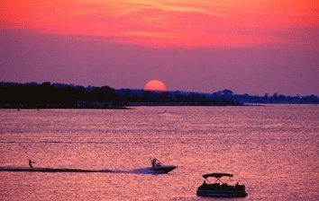 A boat in the water with the sun setting behind it.