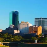 A city skyline with tall buildings and grass.