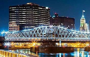 A city at night with a bridge over a river.