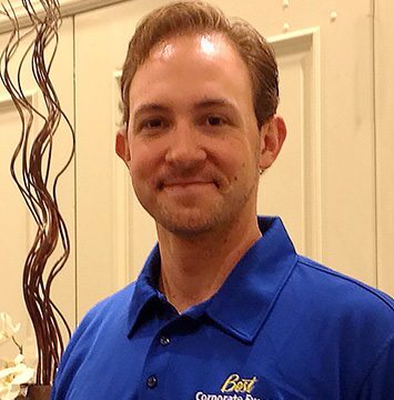 A man in a blue shirt standing next to a vase.