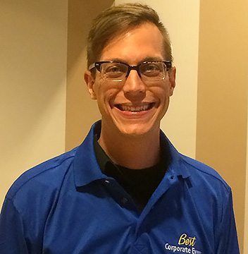 A smiling man wearing glasses and a blue shirt.