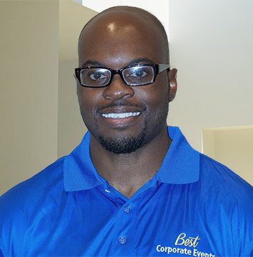 A black man in a blue shirt smiling.