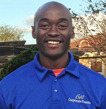 A black man wearing a blue shirt and orange shirt.