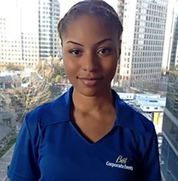 A woman in a blue shirt standing in front of a window.