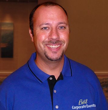 A man in a blue shirt smiling for the camera.