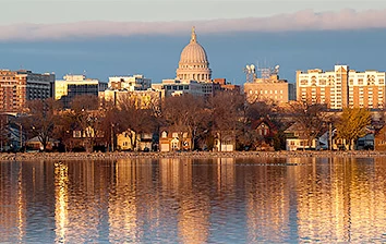 The city of milwaukee is reflected in a body of water.