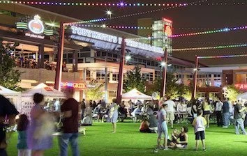 A group of people walking around in a grassy area at night.