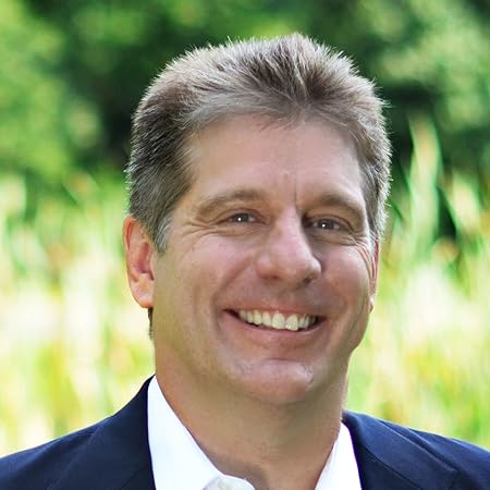A man smiling in front of a green field.