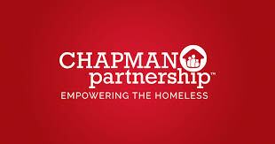 Red background with white text that reads "CHAPMAN partnership" with a house logo and people inside it, followed by "EMPOWERING THE HOMELESS.