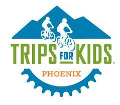 Logo for "Trips for Kids Phoenix" featuring two cyclists on a mountain backdrop and a gear cog at the bottom.
