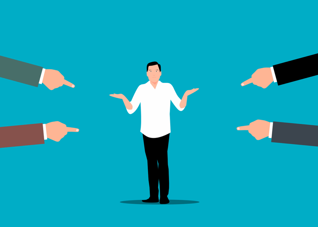 Illustration of a man shrugging with four hands pointing at him from each corner, set against a blue background, capturing the tension between constructive criticism vs destructive criticism.