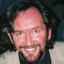 A man with long hair smiling for the camera.