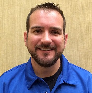 A man in a blue shirt smiling for the camera.