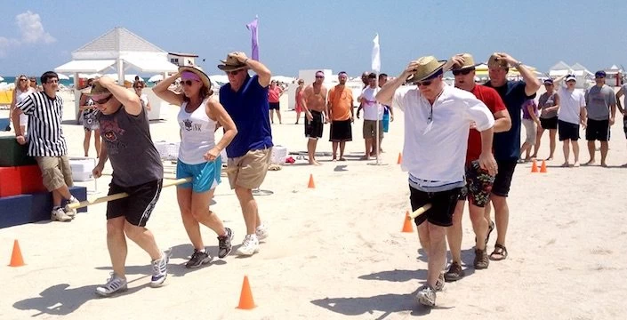 A group of people playing a game on the beach.
