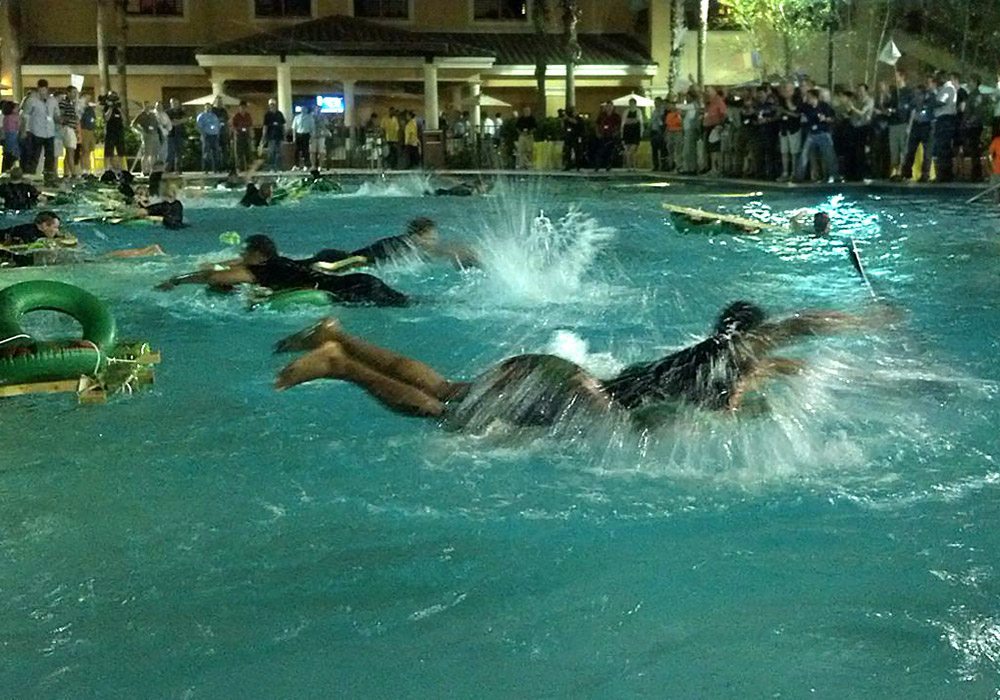 A group of people swimming in a pool at night.