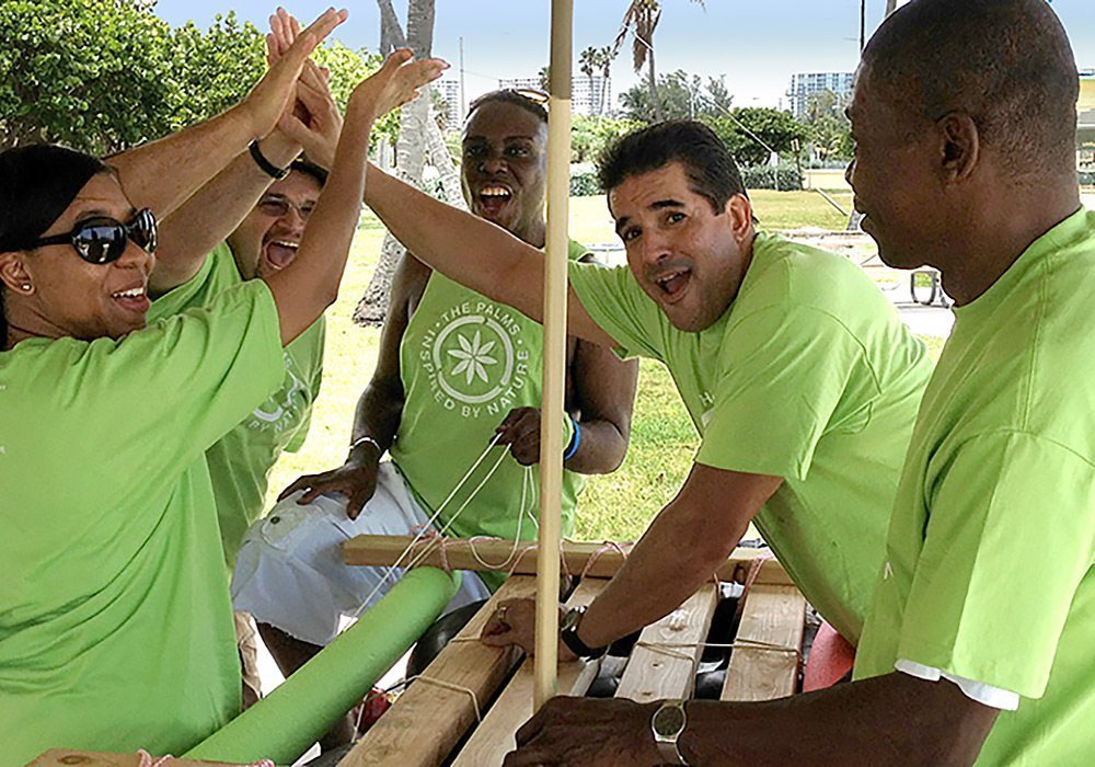 A group of people in green shirts are playing with a wooden stick.