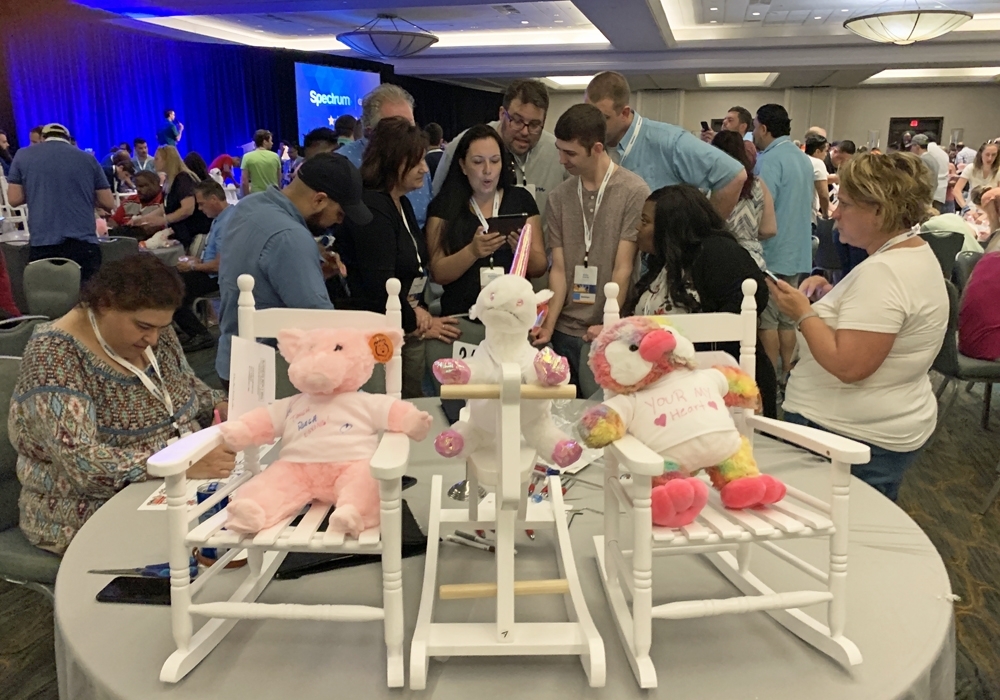 A group of people standing around a table with stuffed animals.