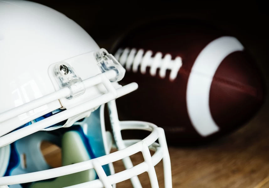 A Super Bowl-themed american football helmet and ball display on a wooden table.