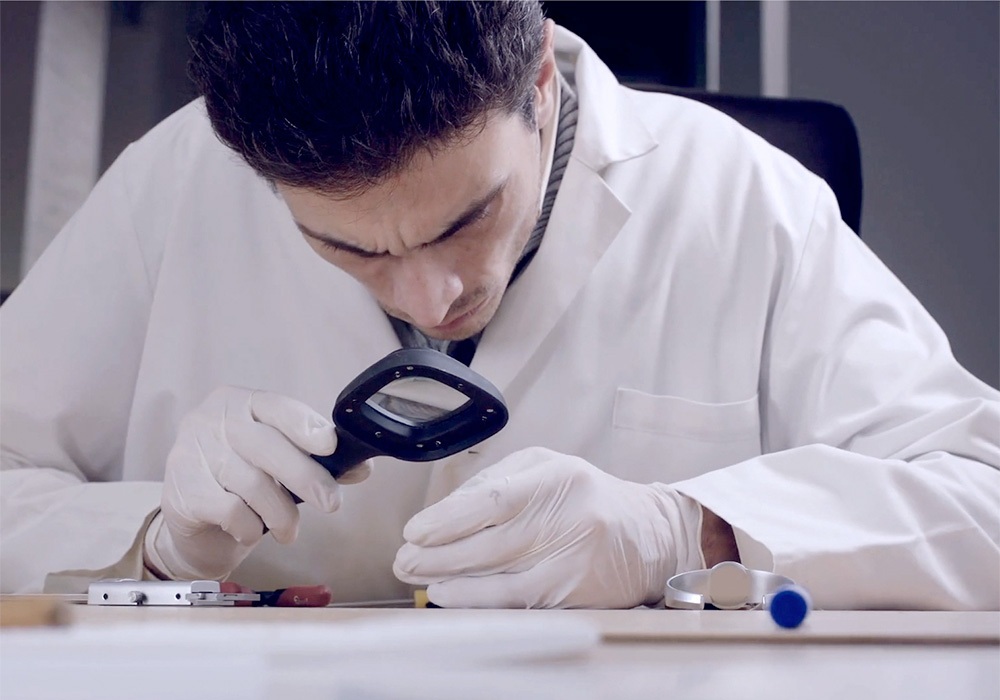 A man in a lab coat looking through a magnifying glass.