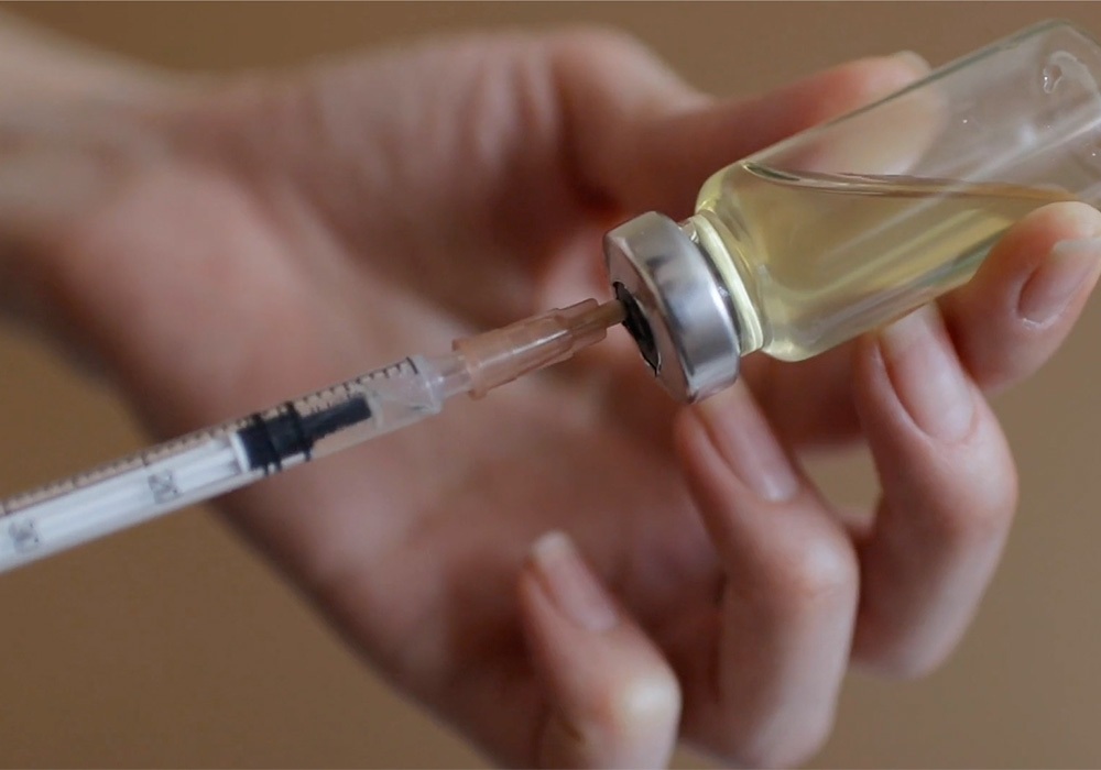 A person holding a syringe with a syringe.