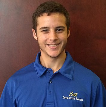 A young man in a blue polo shirt smiling.