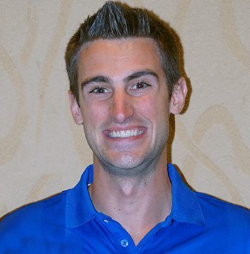 A man in a blue shirt smiling for the camera.
