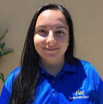 A woman in a blue shirt standing in front of a wall.
