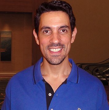 A man in a blue shirt smiling for the camera.
