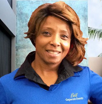 A woman in a blue shirt standing in front of a palm tree.