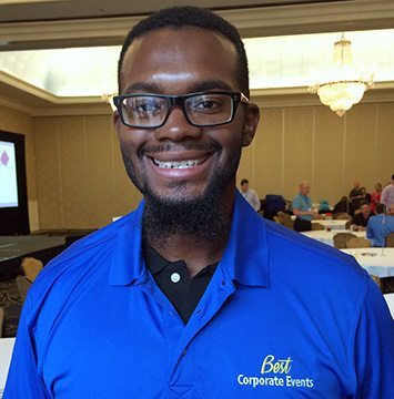 A man in a blue shirt smiling at a table.