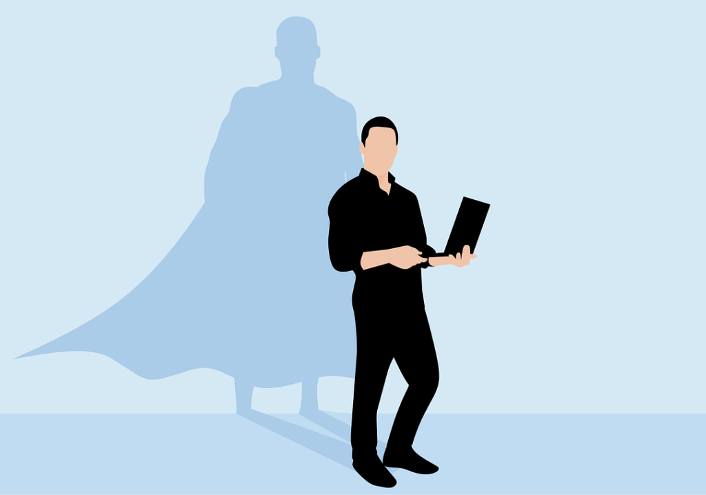 A person stands holding a laptop, their shadow behind them in the shape of a superhero wearing a cape—rising above the challenges of a bad boss.