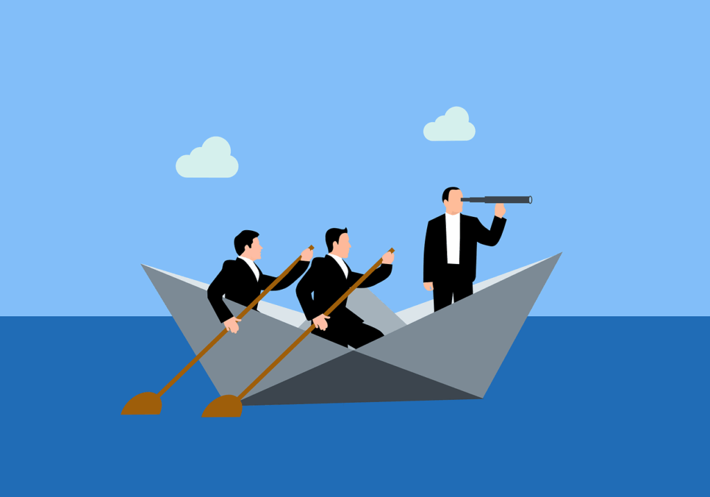 Three men in business suits sit in a paper boat on water; two row with paddles while one stands, looking ahead through a telescope, symbolizing leadership and teamwork found in team building activities.