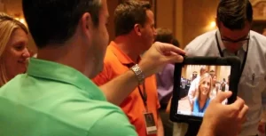 A man is taking a picture of a woman with an ipad.