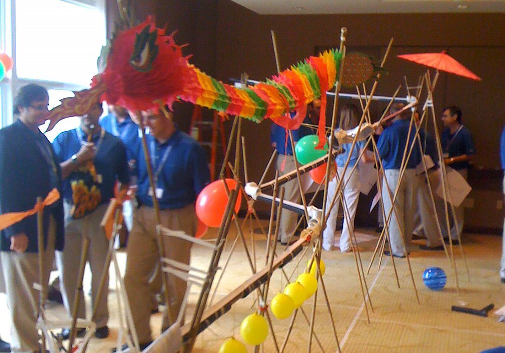 A group of people standing in a room with a bunch of sticks and balloons.