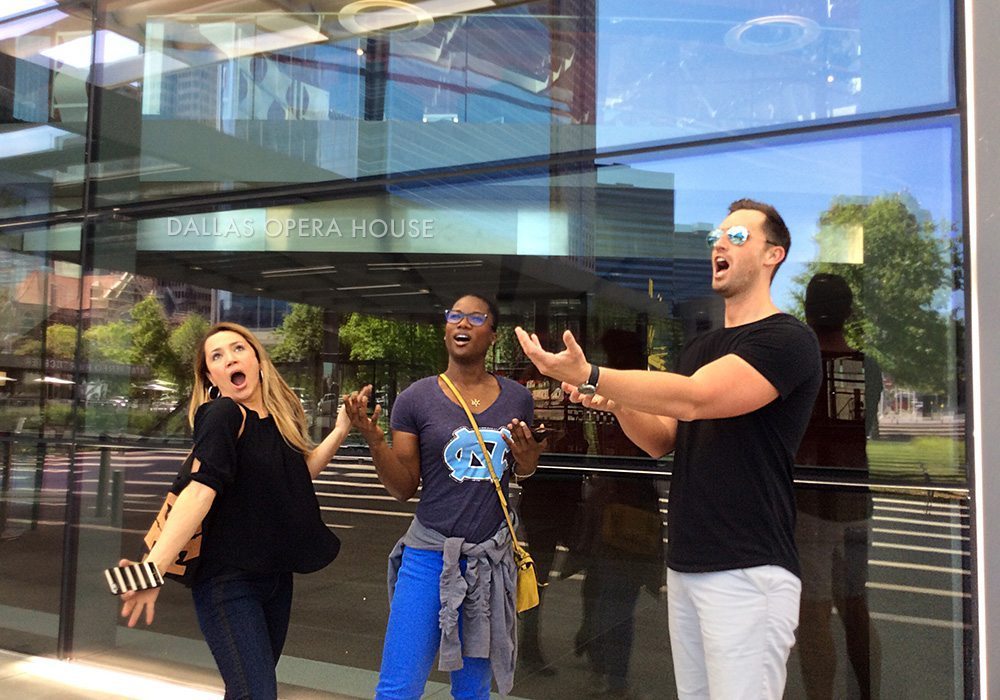 Three people standing in front of a glass building.
