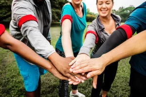 A group of people participating in team building exercises, putting their hands together in a circle.