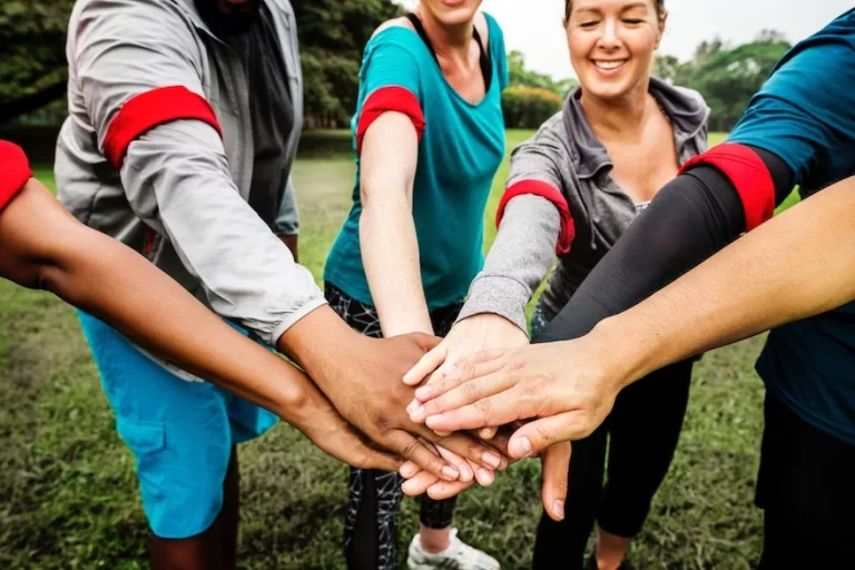 A group of people participating in team building exercises, putting their hands together in a circle.
