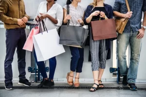 A group of people in a crowded store on Black Friday, enthusiastically holding shopping bags.