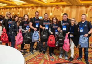 A group of people posing with STEM backpacks in a conference room.