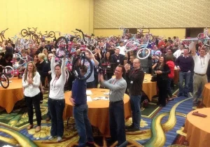 A group of people holding up bicycles in a room.