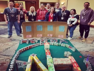 A group of people posing in front of a table full of cans.
