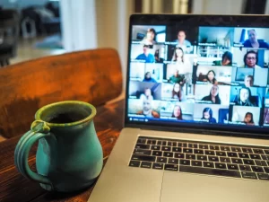 A laptop with a group of people on it and a cup of coffee.