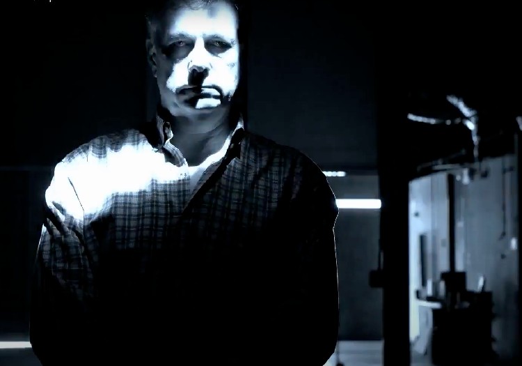 A man standing in a dark room with a flashlight.