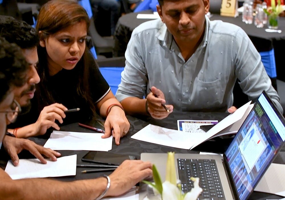 A group of people sitting around a table looking at a laptop.