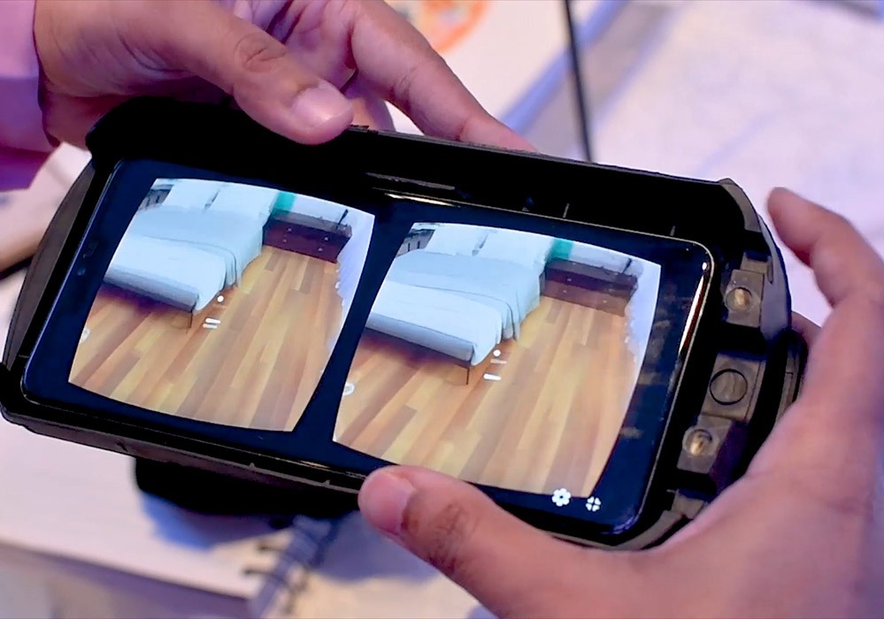 A person holding a smartphone with a vr headset on it.