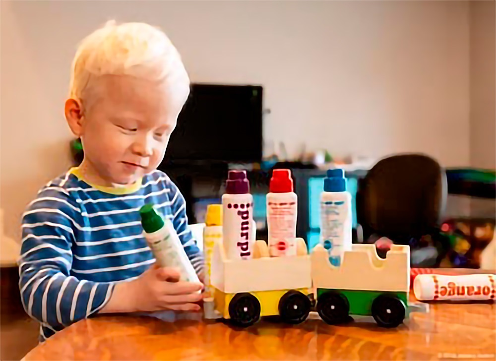 A young boy playing with a wooden train set.